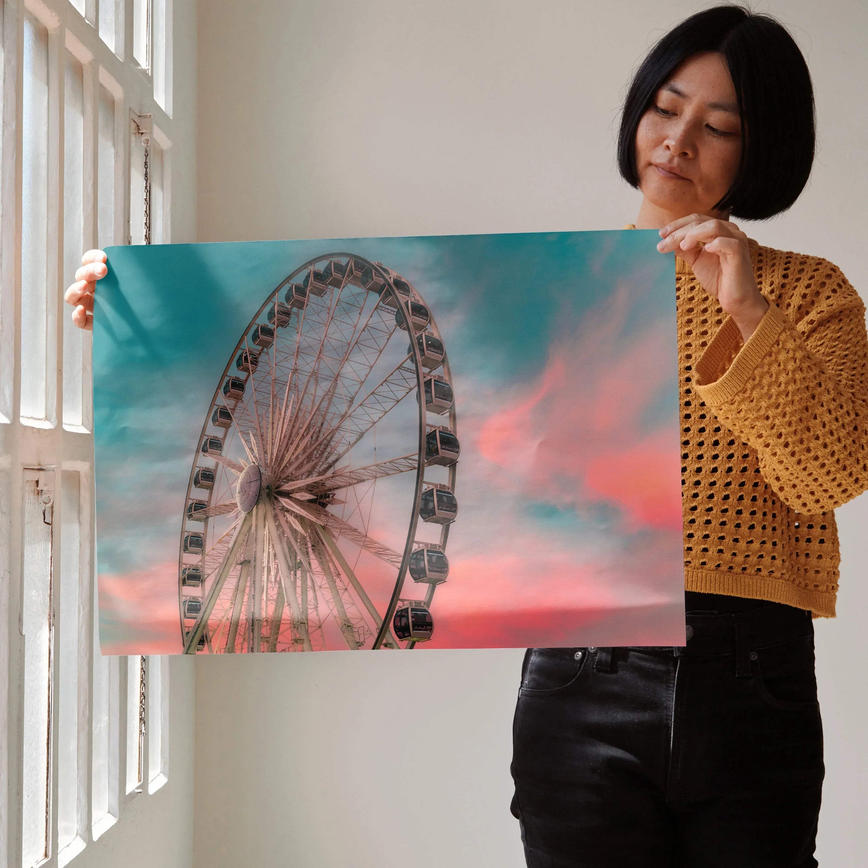 Sunset sky backdrop featuring a Ferris wheel vibrant wall art poster held by woman.