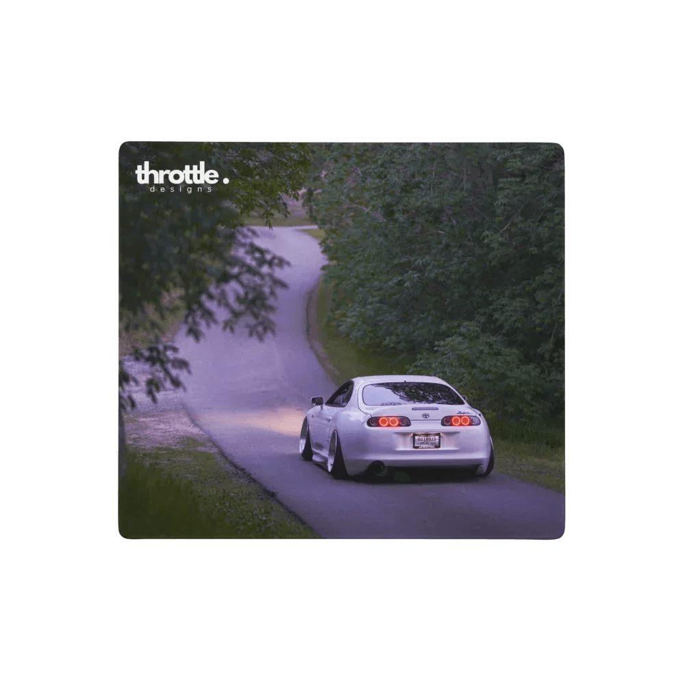 Large extended mouse pad featuring a white Toyota Supra Mk4 driving on a winding tree-lined road at dusk with throttle logo.