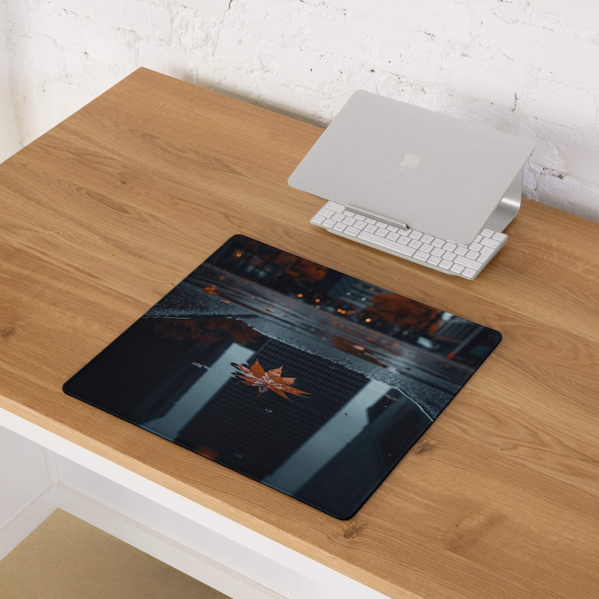 Black rectangular mousepad with glossy orange maple leaf on wet night pavement
