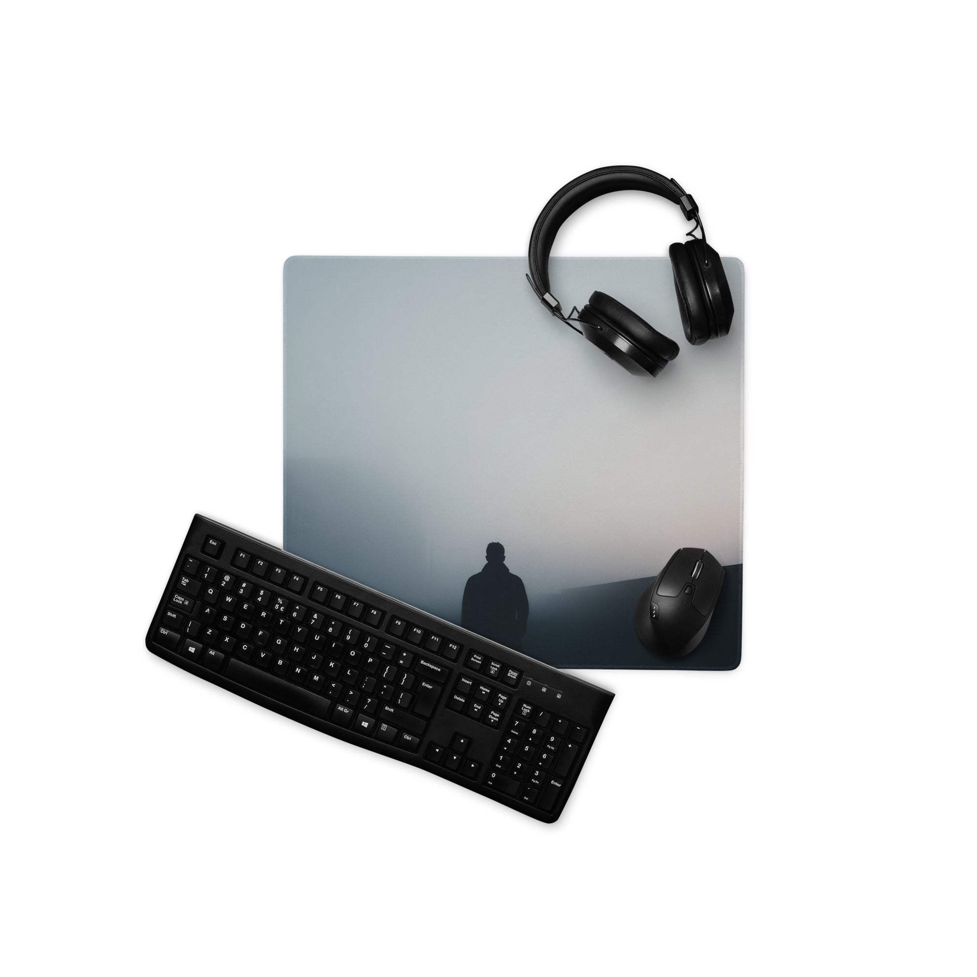 Black keyboard mouse on moody blue gray gaming mouse pad with misty hills silhouette