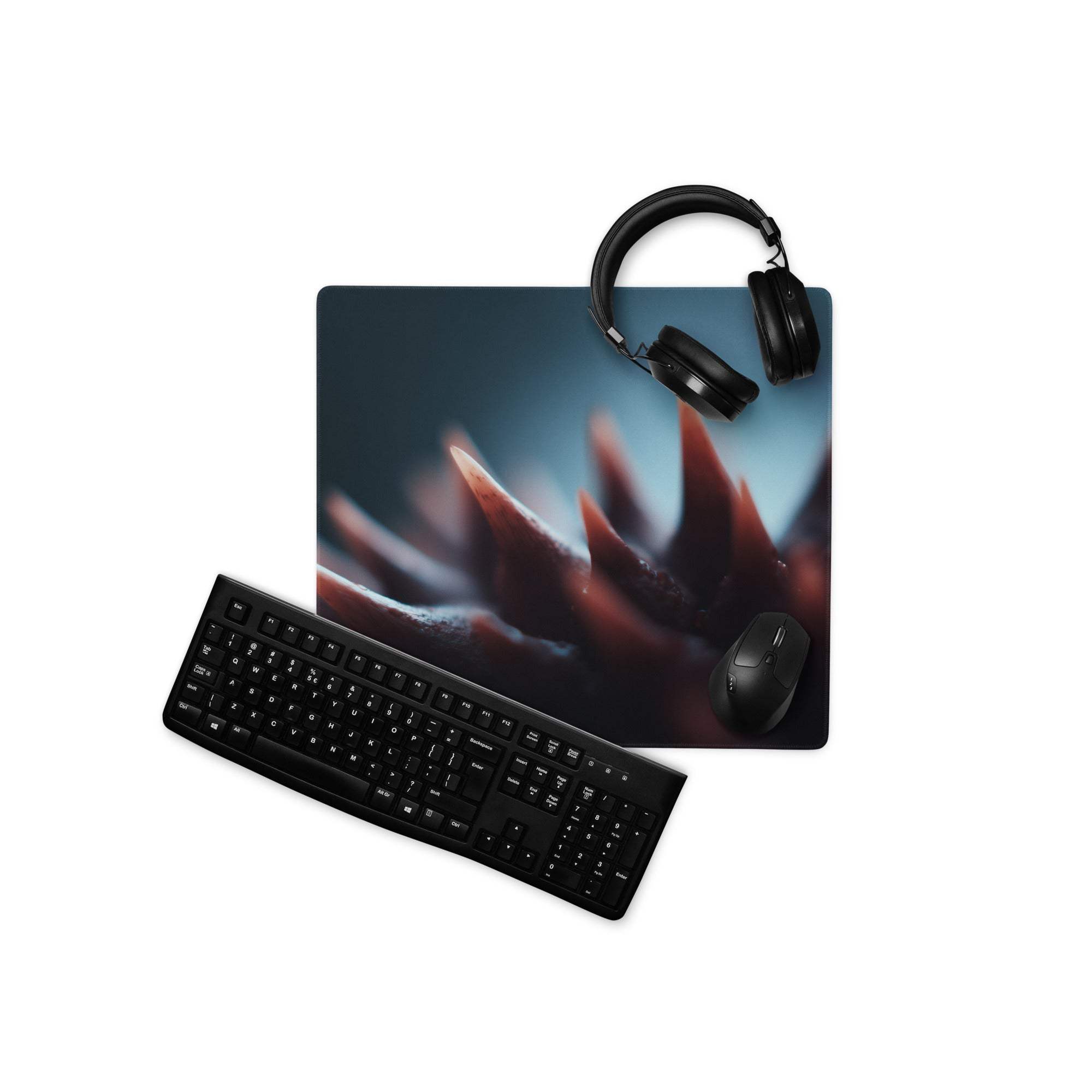 Black gaming mousepad with red blue spiky motifs, headphones on top