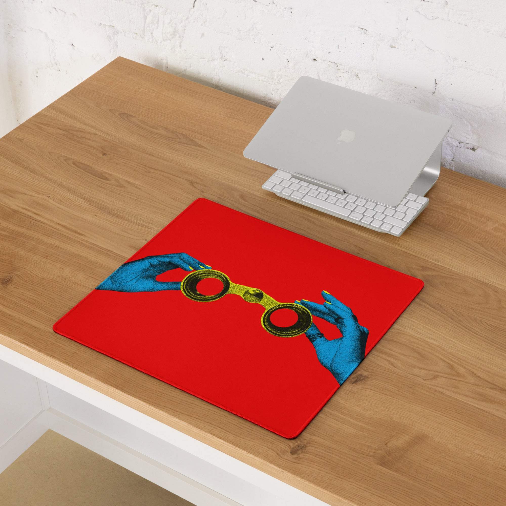 Red rectangular mousepad with a vibrant blue hands graphic holding gold-rimmed spectacles for bold desk decor