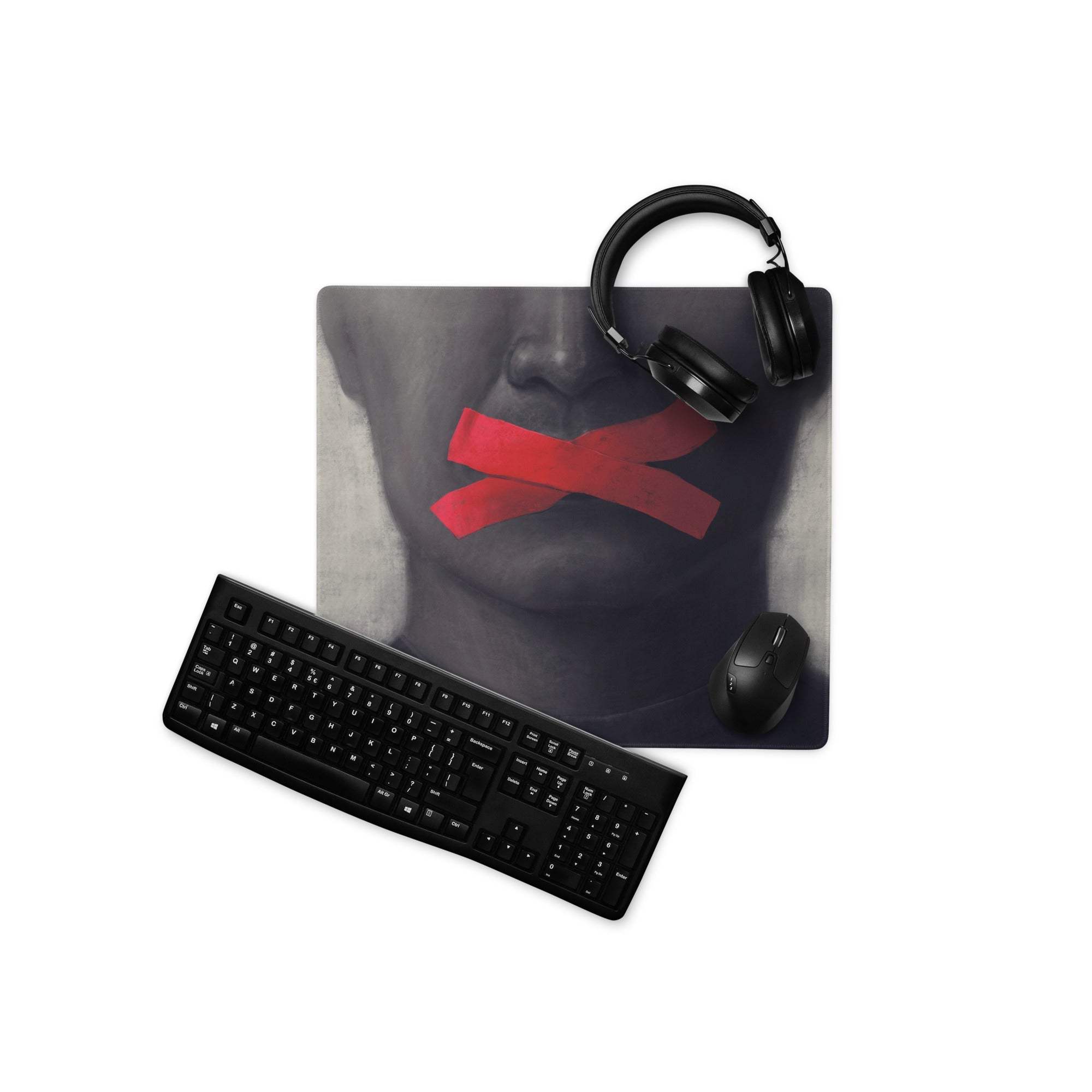 Black textile industrial edge tape art mouse pad with grayscale face and red tape, paired with black headphones and keyboard