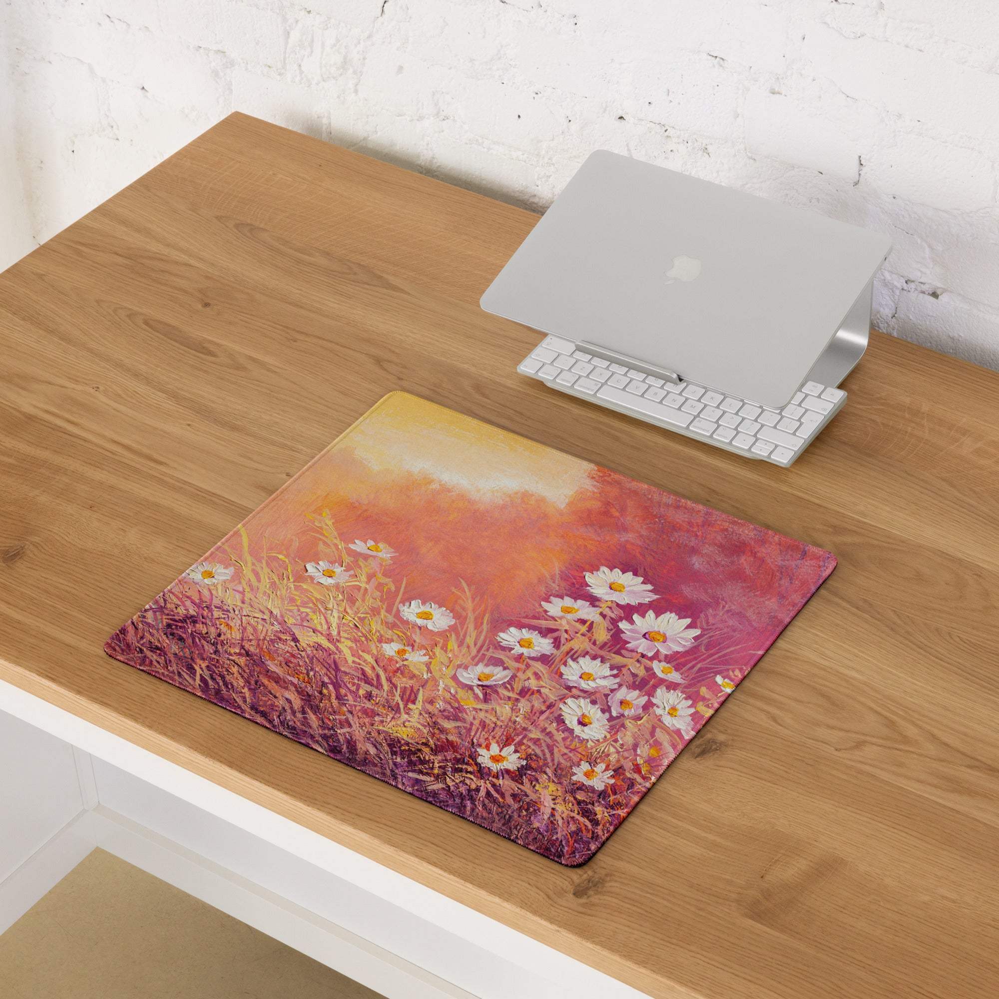 A rectangular acrylic floral sunset daisy desk pad with white daisies and golden grasses on an orange pink gradient background