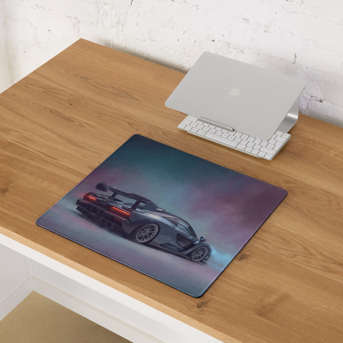 Mclaren senna inspired apex stealth desk pad featuring a sleek dark gray sports car graphic with red taillights on a smoky background