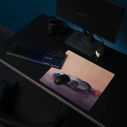 A sleek rectangular silver gaming mousepad featuring a silver sports car with glowing red taillights at sunset