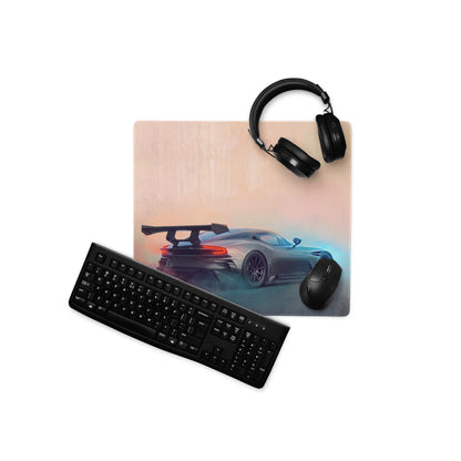 Rectangular gunmetal gaming mousepad with stitched edges featuring a silver aston martin vulcan car on peach-blue background