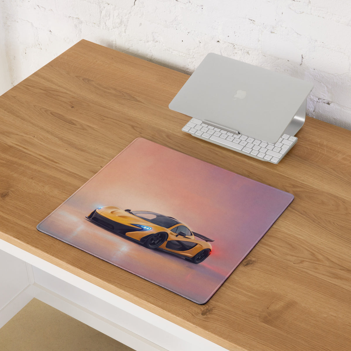 A rectangular low-friction cloth mousepad with vibrant yellow and black McLaren P1 graphic on a pink orange gradient background