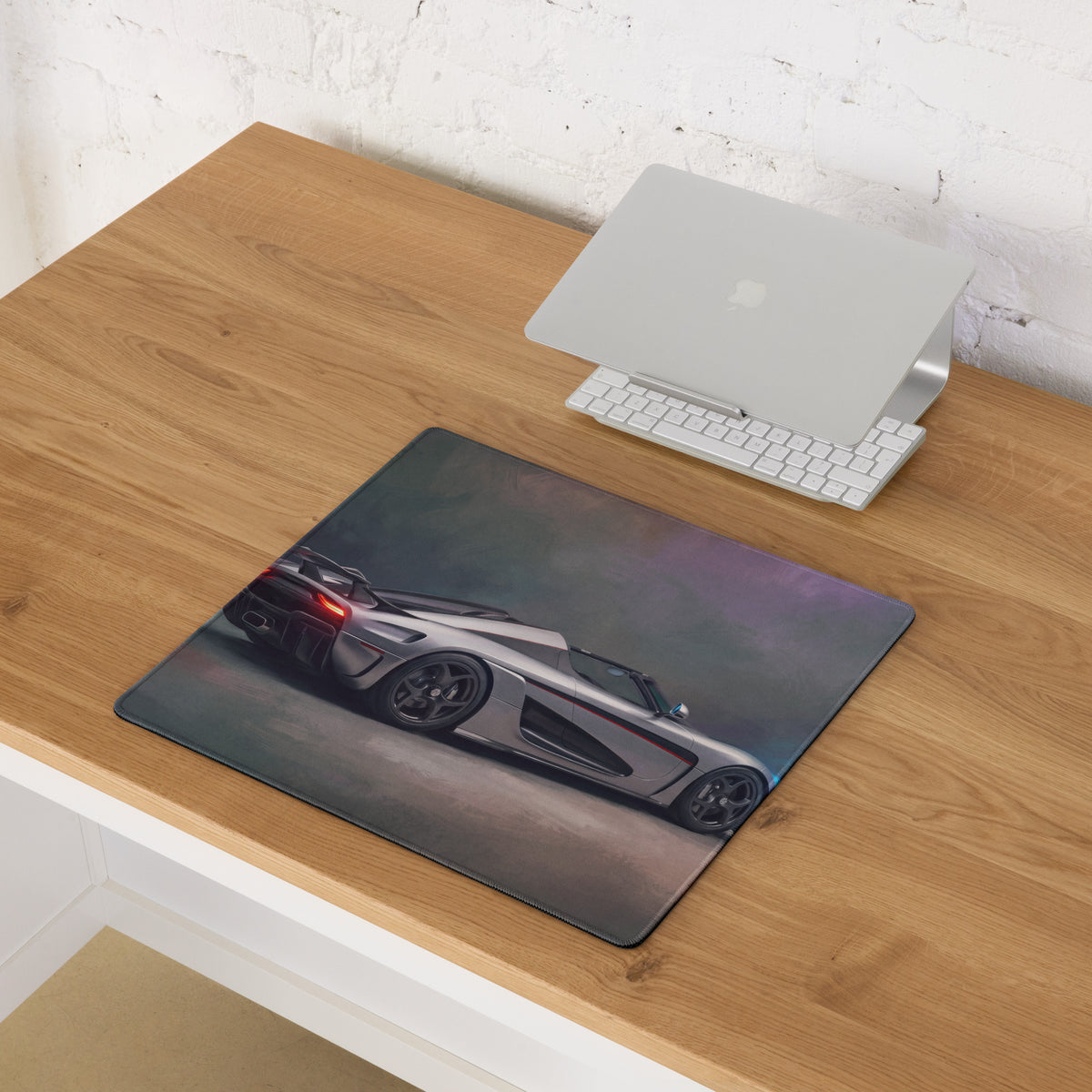 A sleek rectangular silver and black koenigsegg agera rs rear desk mat with glowing red taillights for gaming use