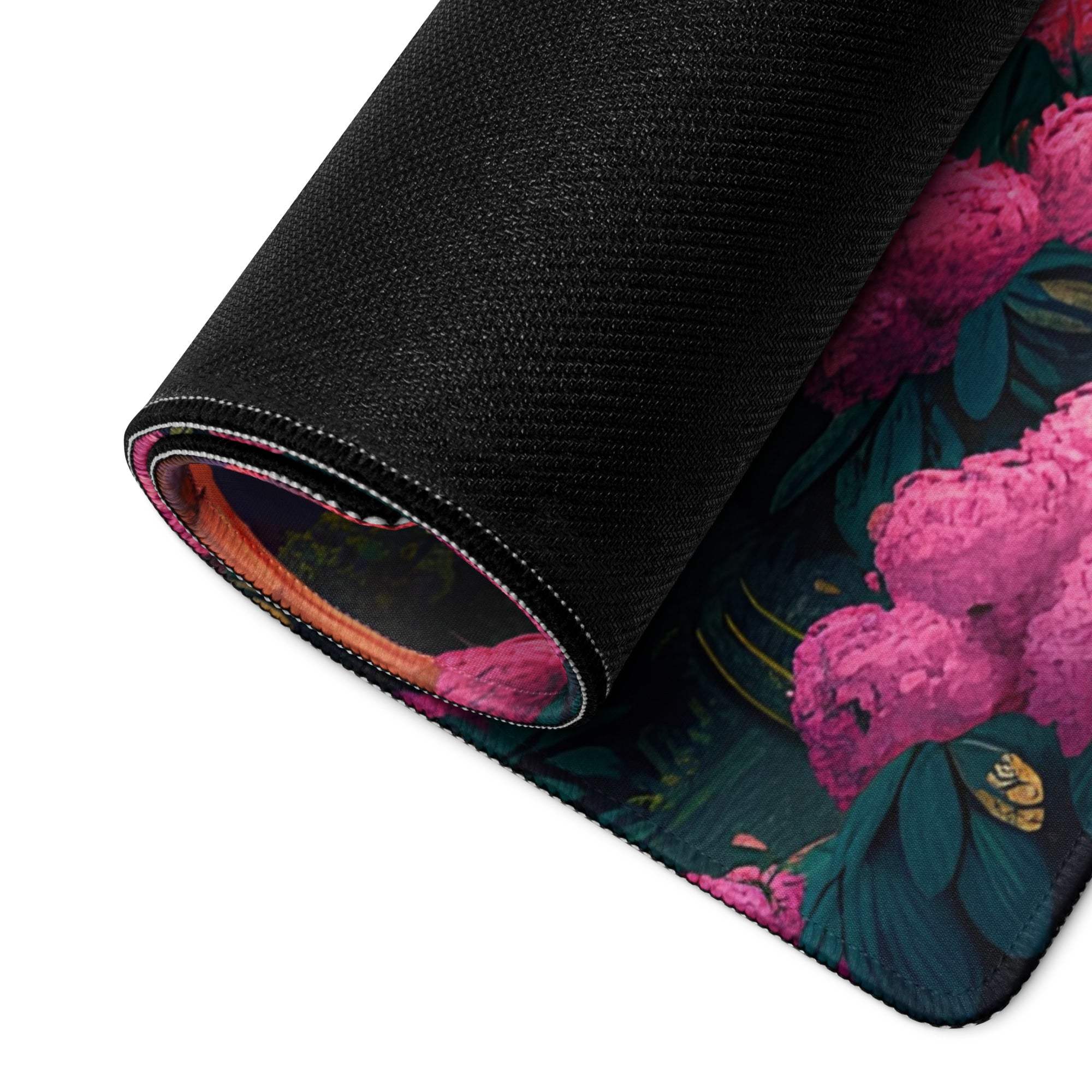 Rolled-up black mousepad with pink peonies, teal leaves, hills, sunset gaming design
