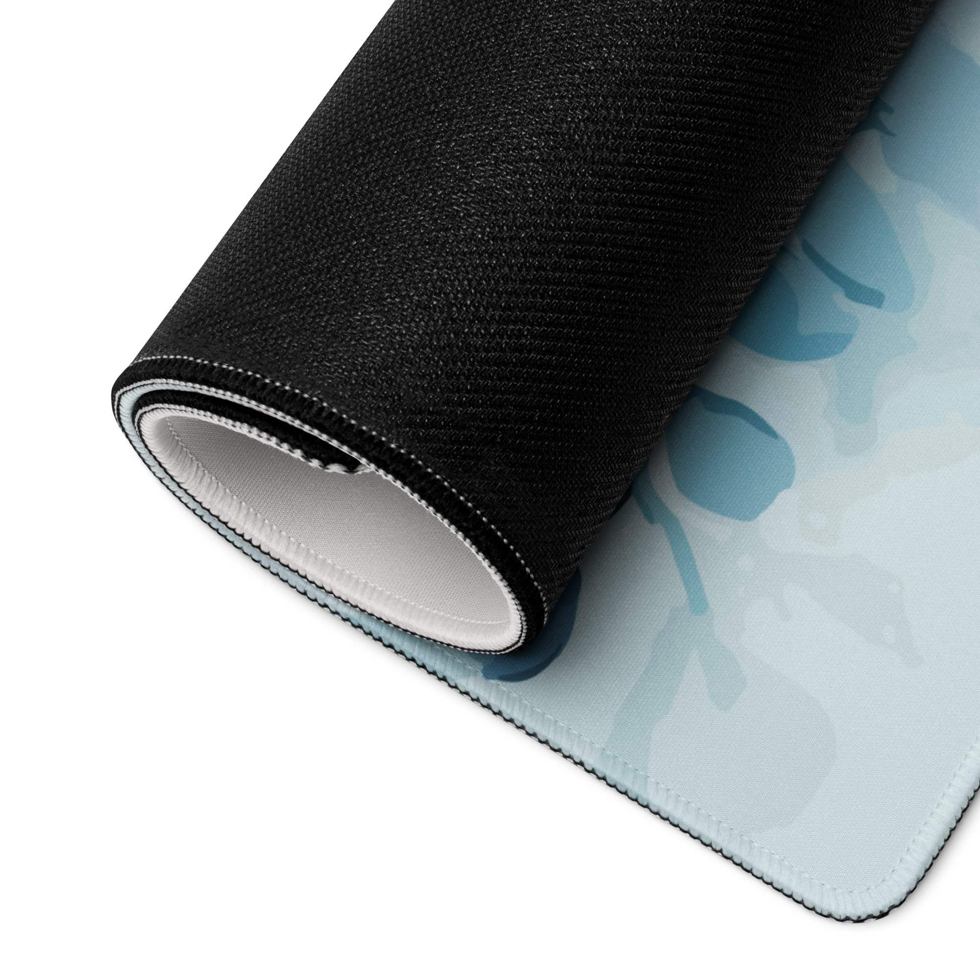 Rolled-up blue floral large gaming mouse pad with white edge stitching