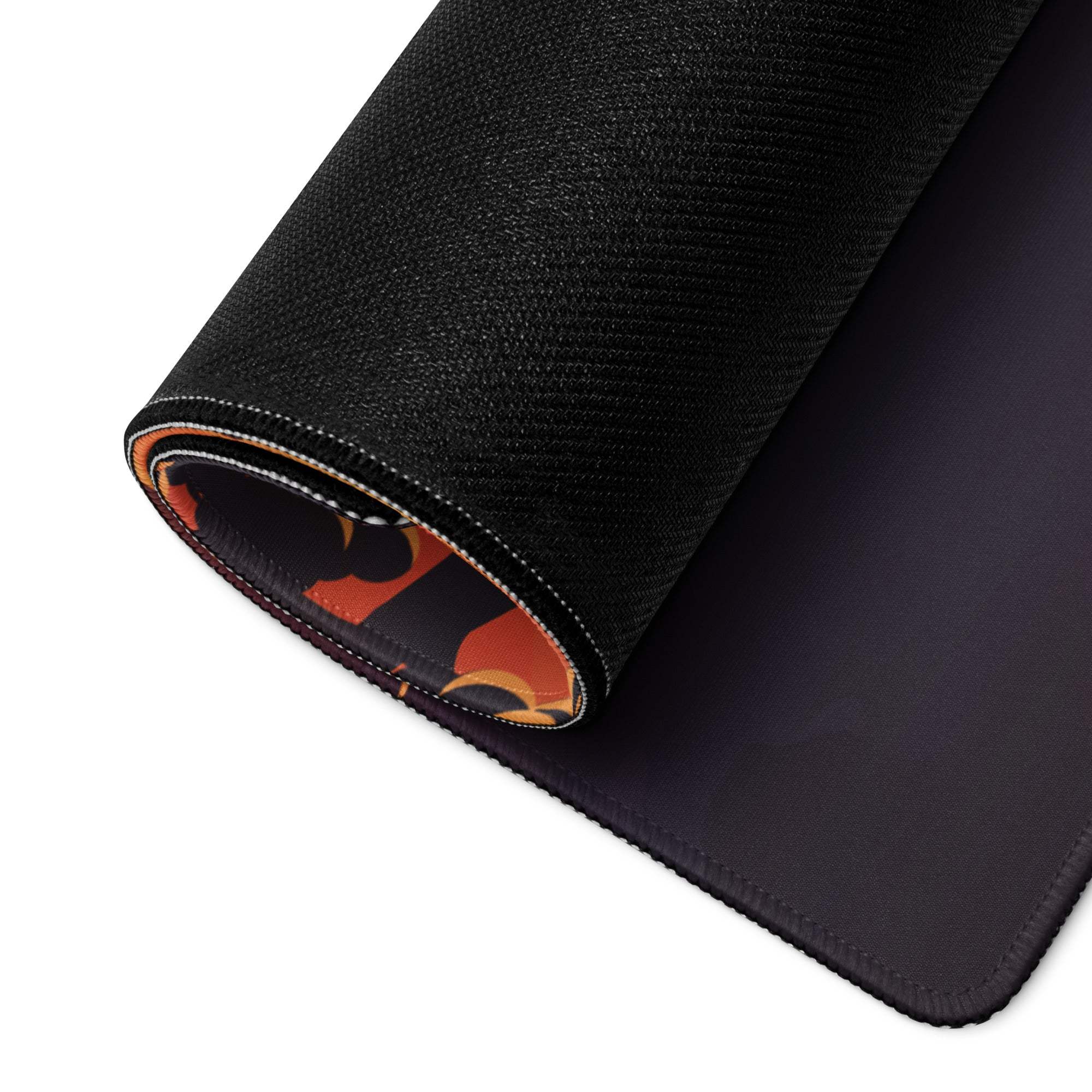 Black textured gaming mousepad with rolled edge revealing orange black flame pattern
