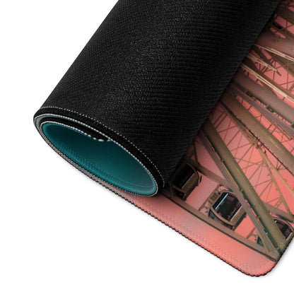 Black textured gaming mousepad with teal rolled edge and pinkish-orange Ferris wheel print