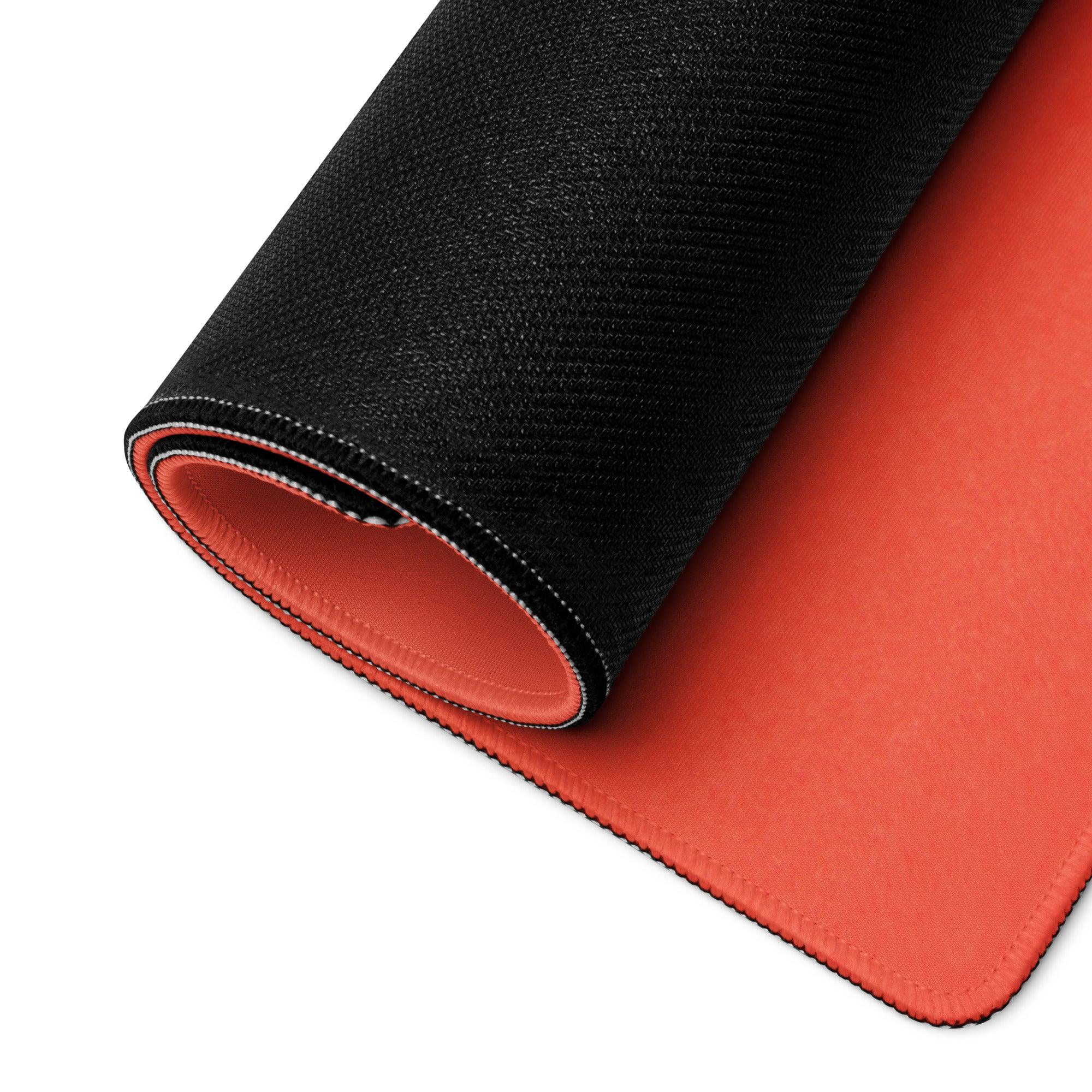 Black and orange gaming mousepad with non-slip base on red backdrop