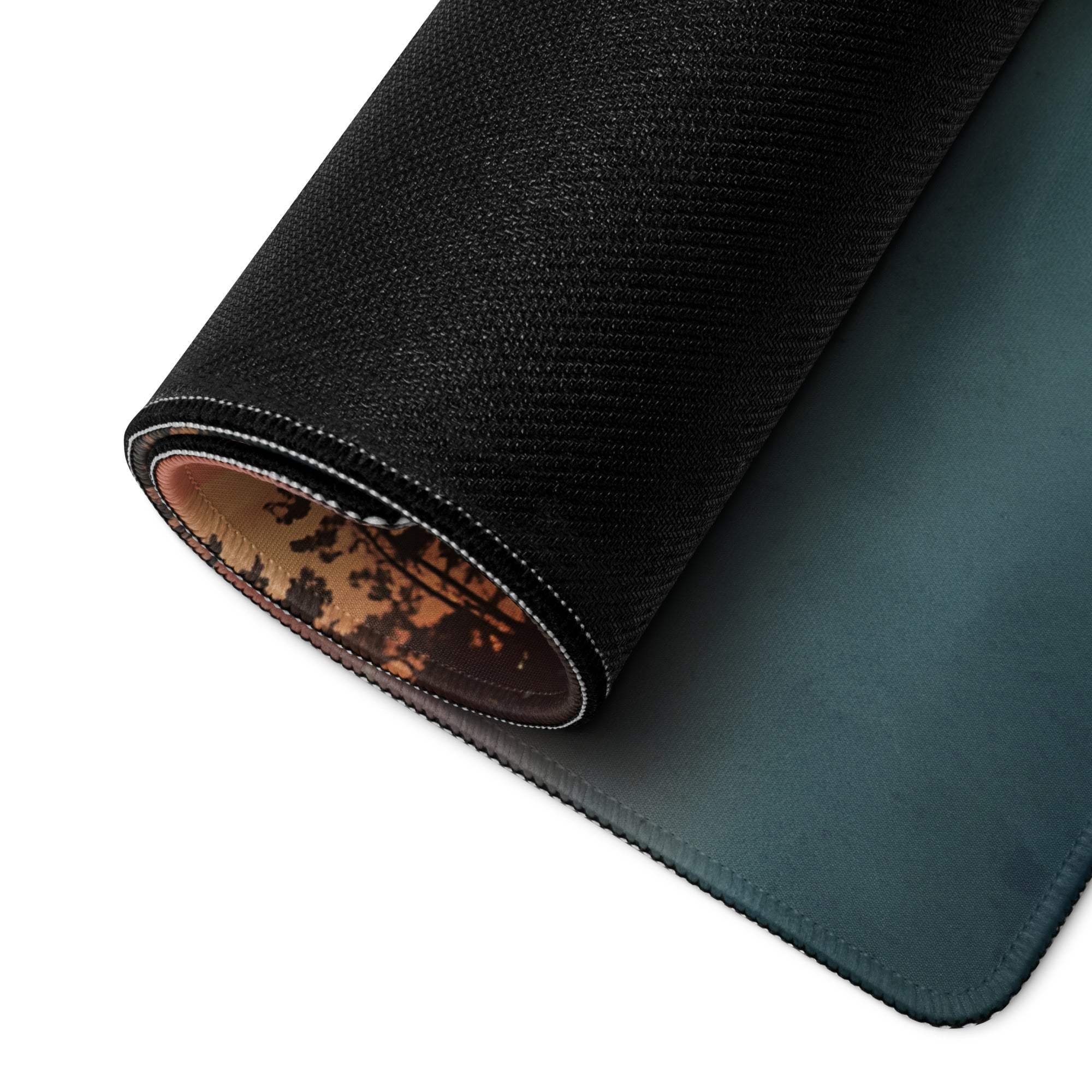 Black textured gaming mousepad with teal gradient, stitched edges, forest lining