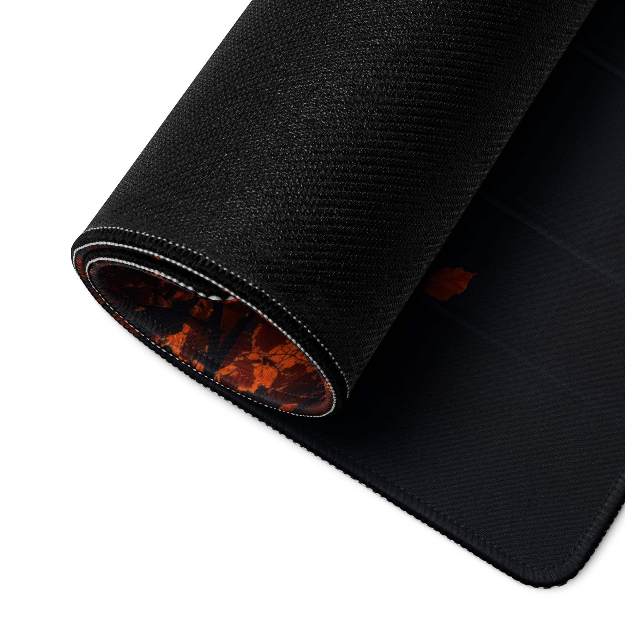 Black textured gaming mousepad with orange leaf pattern on rolled edge