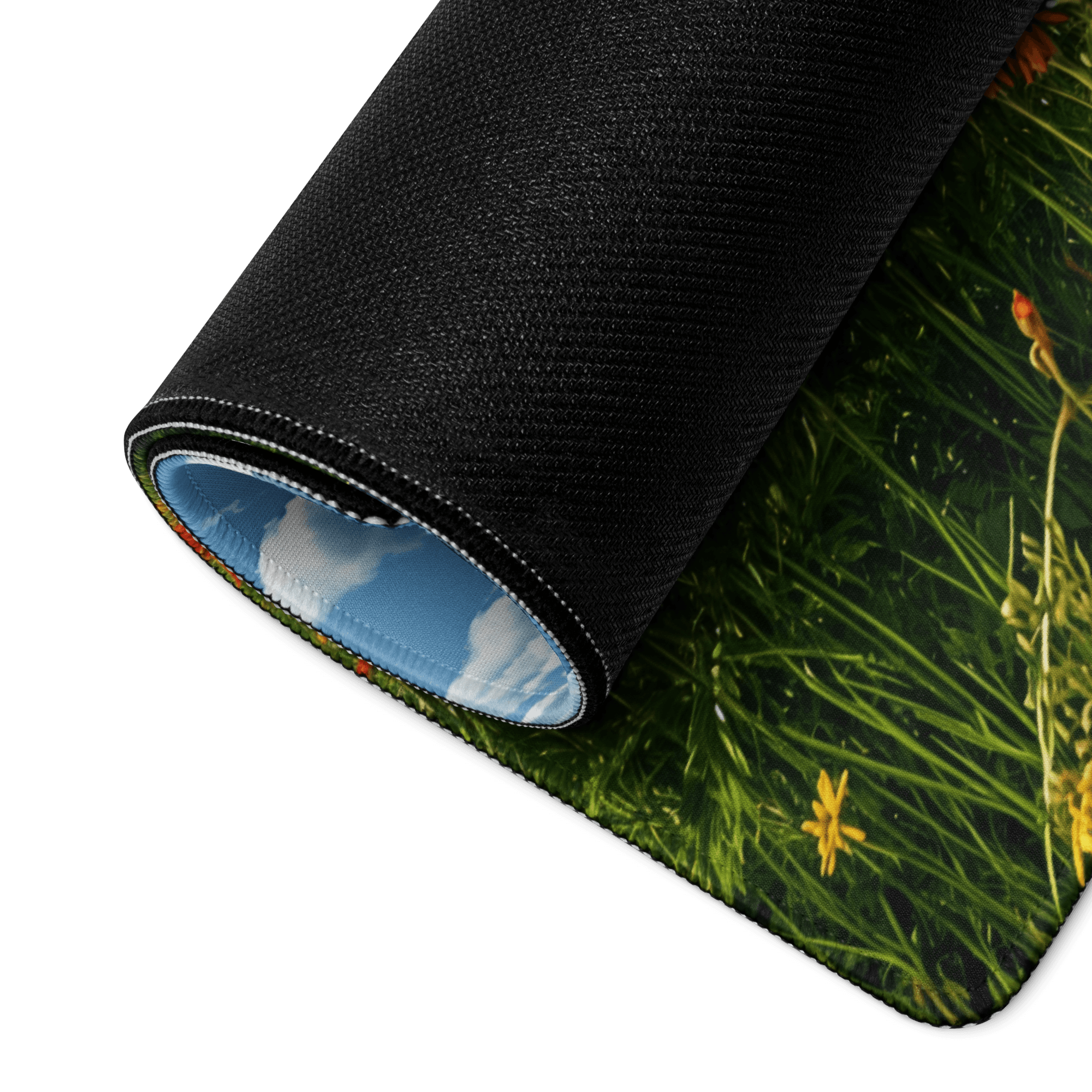 Black rolled-up mousepad with green grass, yellow flowers, blue sky lining