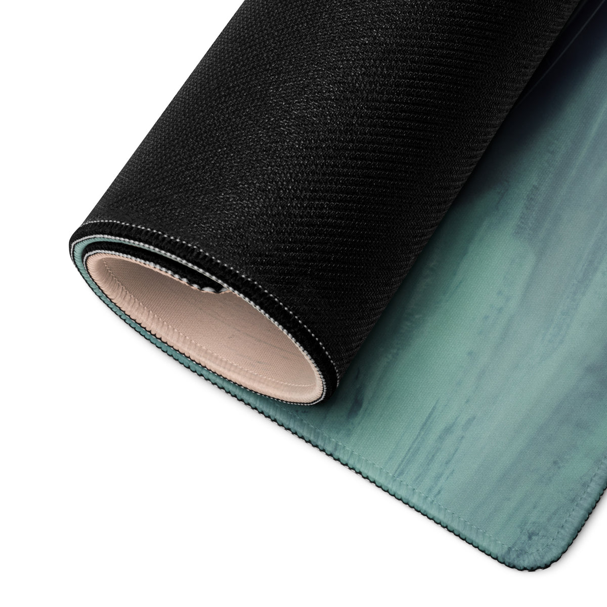 Rolled-up mercedes-amg gt inspired carmine beast desk pad in black and teal gradient with stitched edges and textured surface