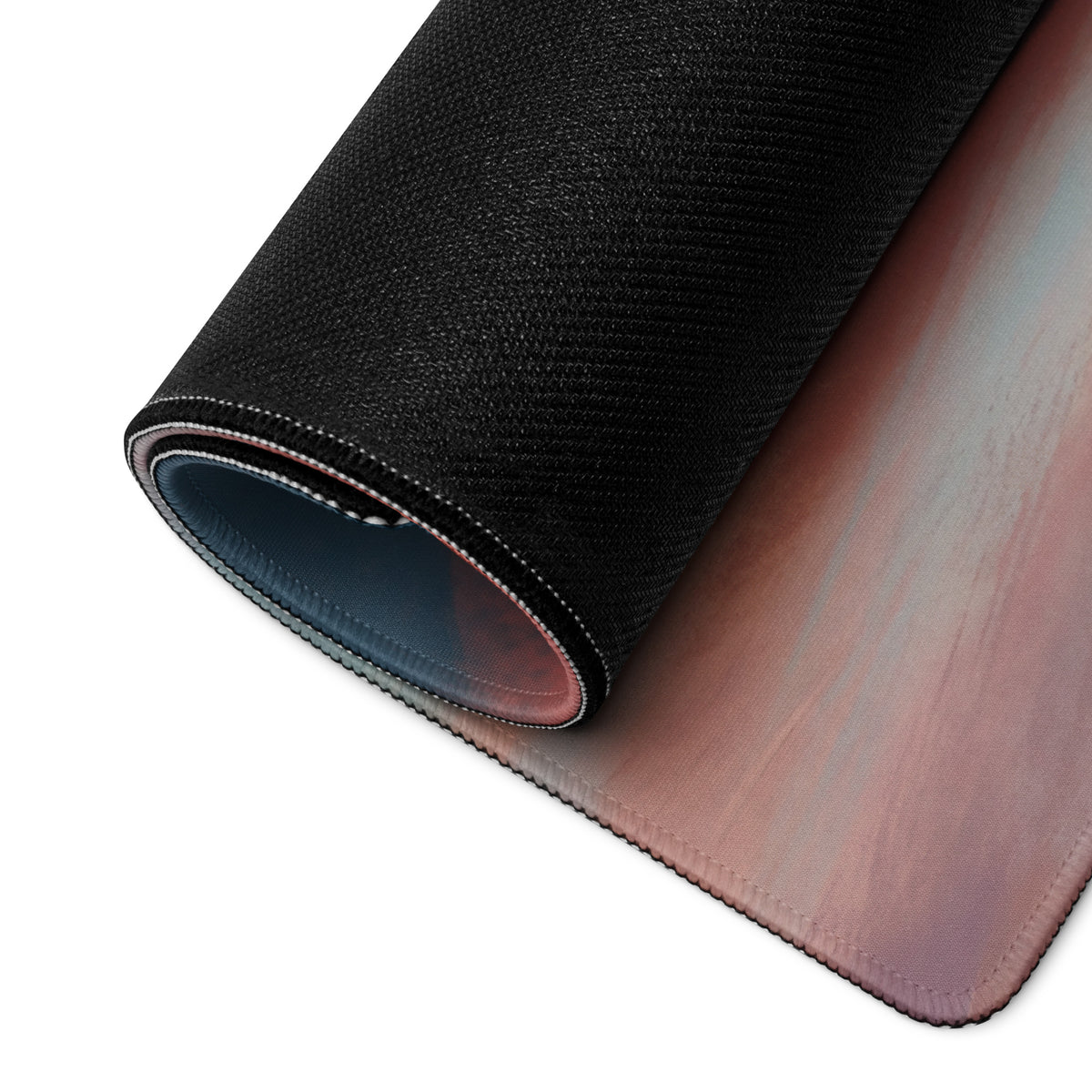 A rolled-up porsche 911 gt3 rs inspired irish green desk pad with gradient pink and purple surface and stitched edges
