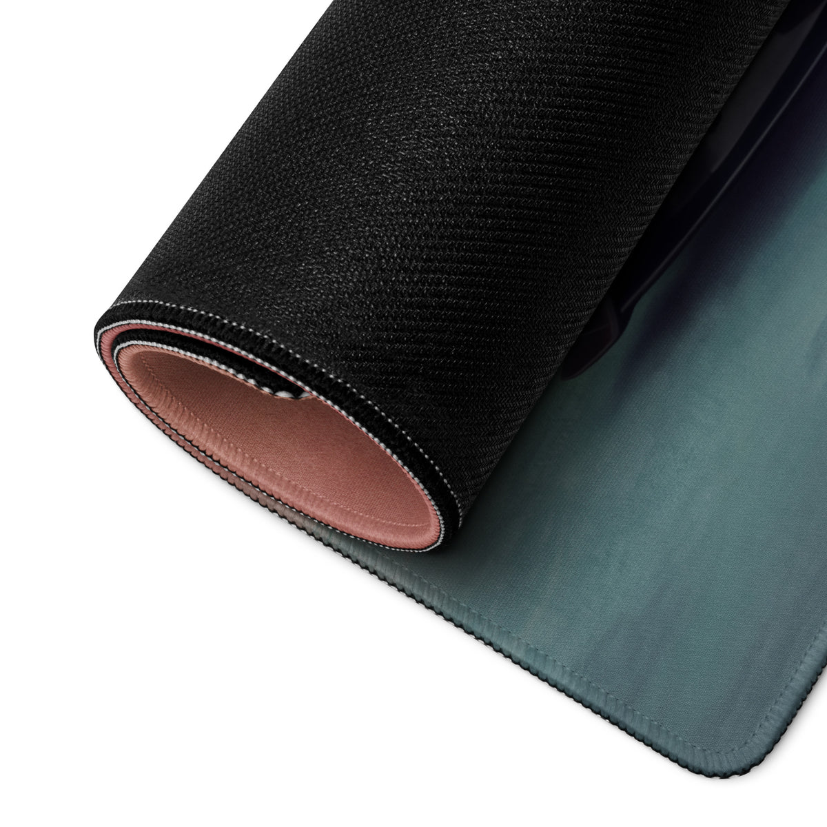 Black textured stealth onyx desk mat with soft pink interior lining rolled to showcase sleek low-friction cloth design