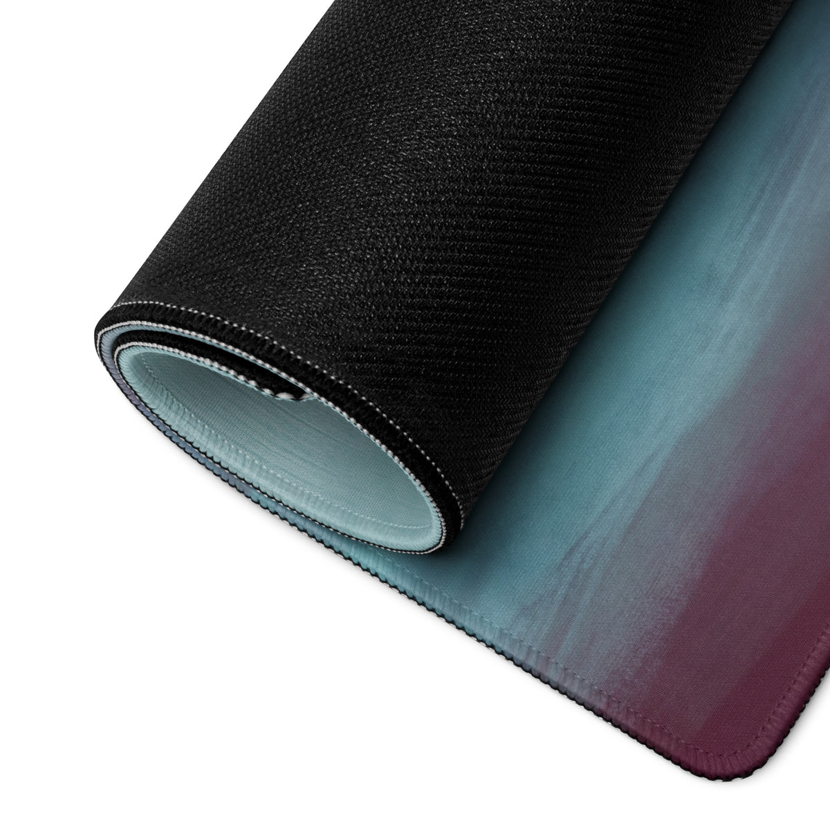 A rolled-up lamborghini centenario inspired carbon gold desk mat with a teal to deep purple gradient surface