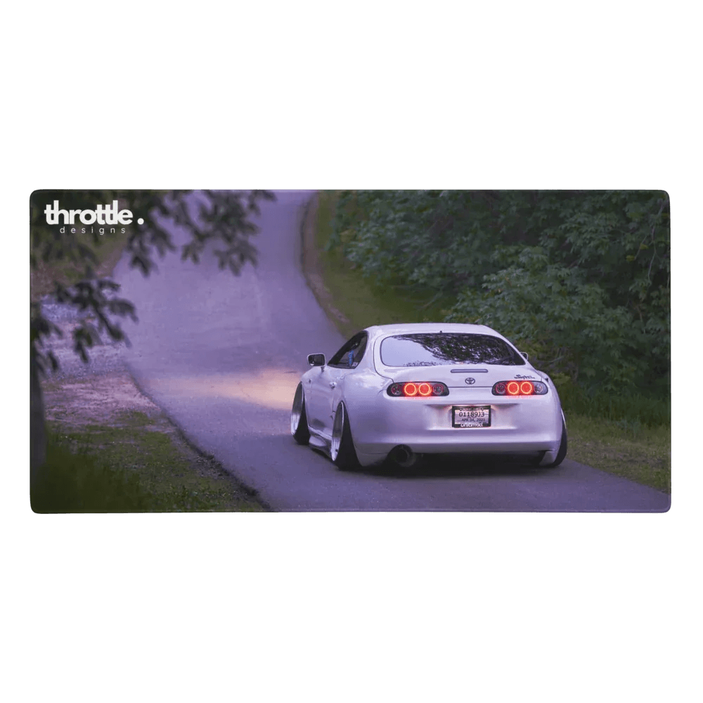 Extended gaming mouse pad featuring a white Toyota Supra Mk4 driving on a forest road at dusk.
