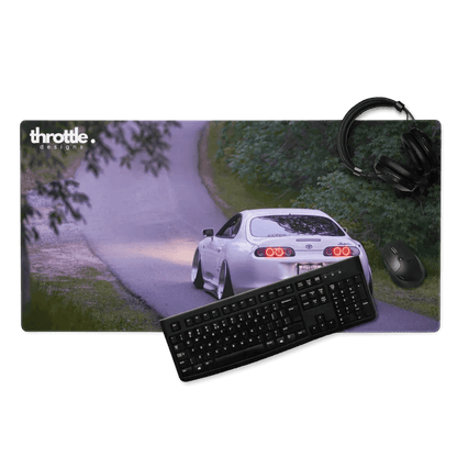 Extended gaming mouse pad with white Toyota Supra Mk4 rear view on winding road under trees.
