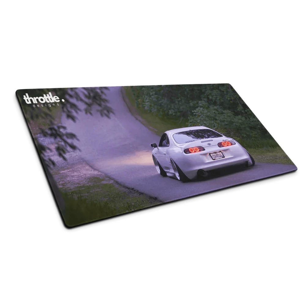 Large gaming mouse pad featuring a silver Toyota Supra Mk4 driving on a winding road with greenery background.