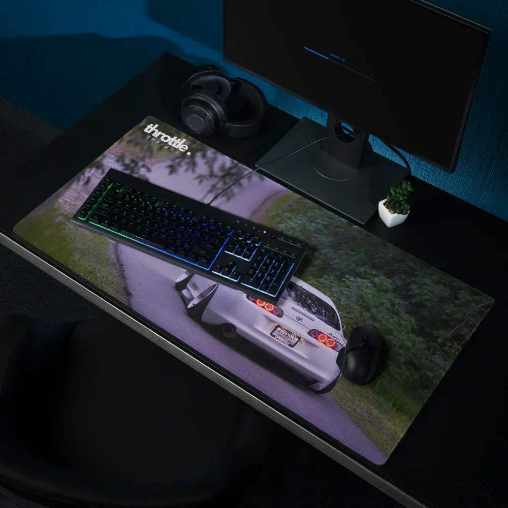 Large gaming mouse pad featuring a rear view of a white Toyota Supra Mk4 on a dark asphalt background.