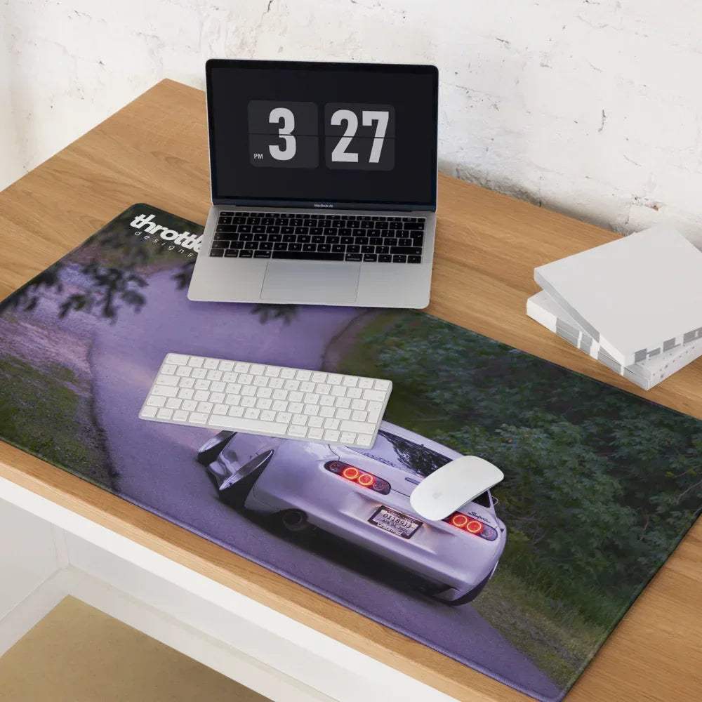 Large gaming mouse pad featuring white Toyota Supra Mk4 rear on forest road background.