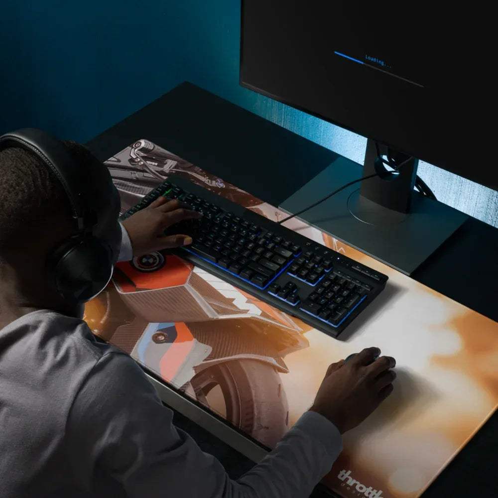 Black keyboard with blue backlighting on a large bmw inspired m1000rr gaming mouse pad featuring orange brown mechanical design