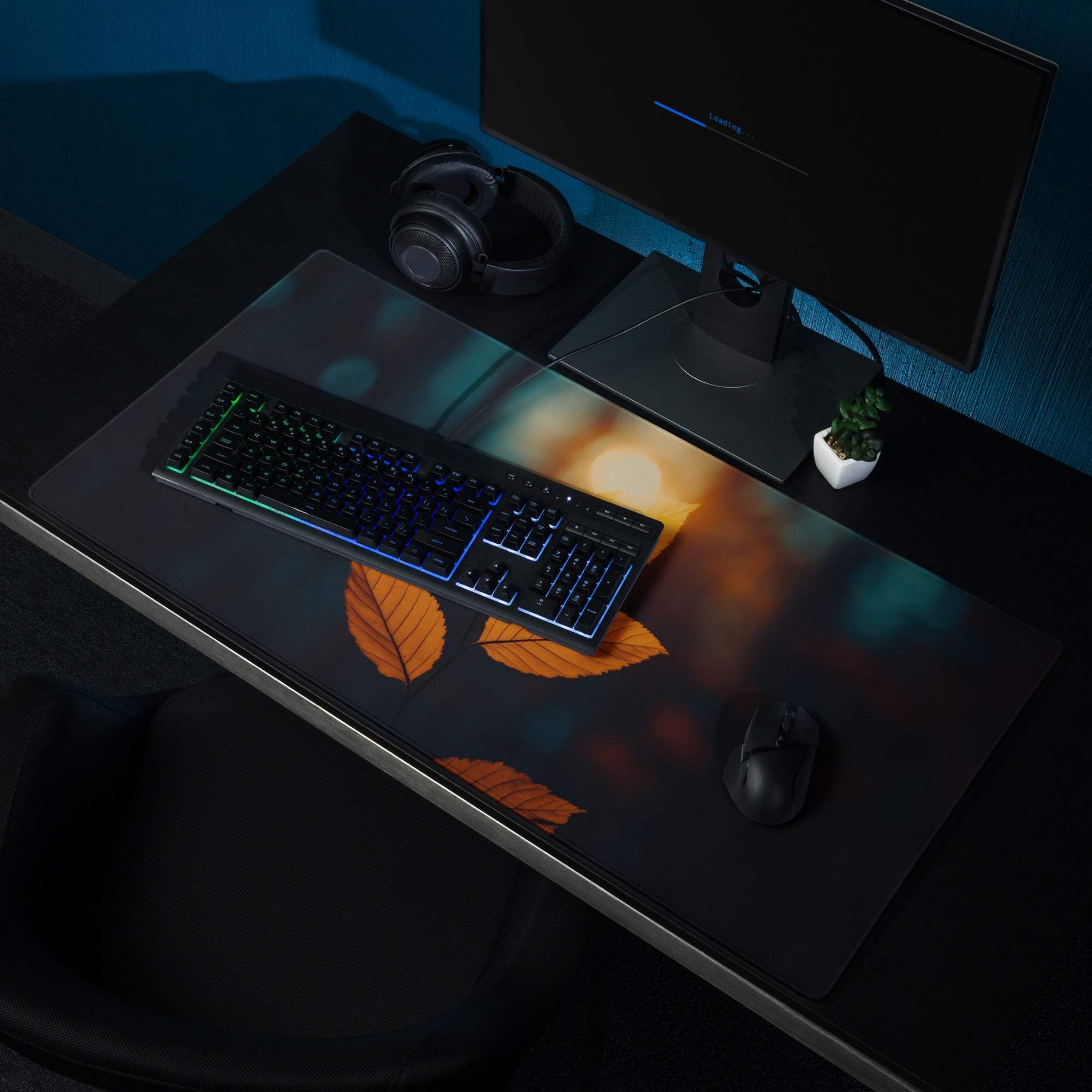 Large black gaming mouse pad with orange autumn leaf design and glowing bokeh background
