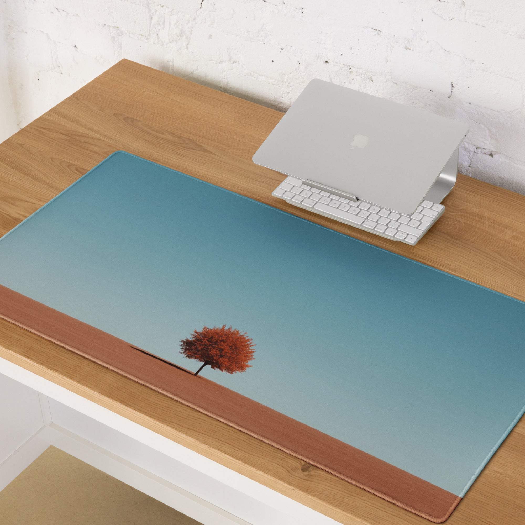 Minimalist blue gradient desk mat with orange tree silhouette and leather trim