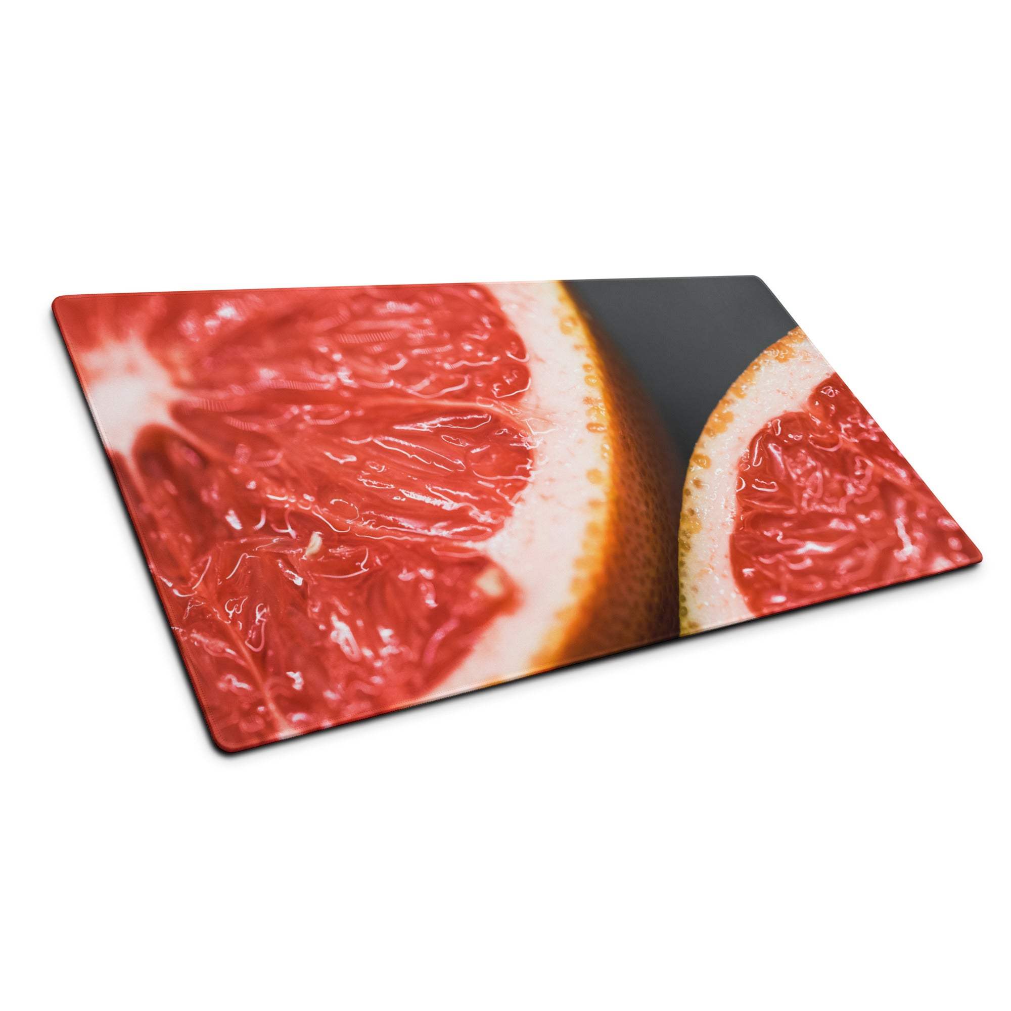 Vibrant sliced pink grapefruit on rectangular glass cutting board, dark background