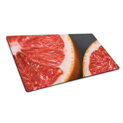 Vibrant sliced pink grapefruit on rectangular glass cutting board, dark background