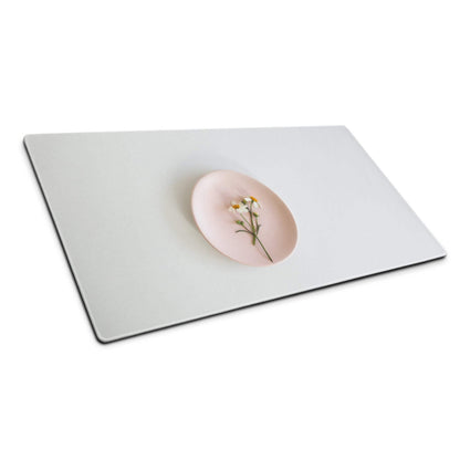 Dried chamomile flowers on pink glossy plate atop soft gray gaming mouse pad