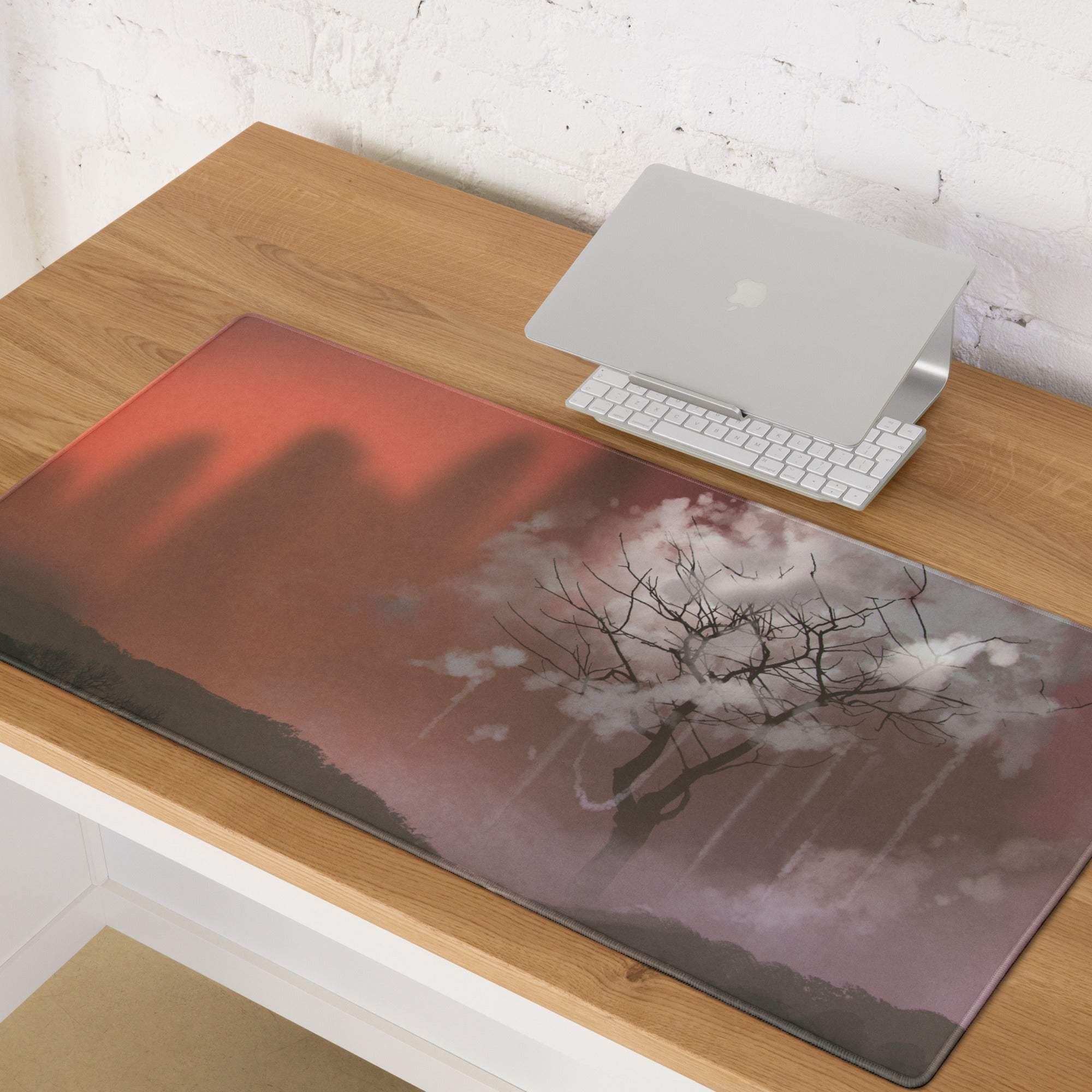 A rectangular glossy red-orange gaming mousepad with a dramatic sunset silhouette tree landscape design