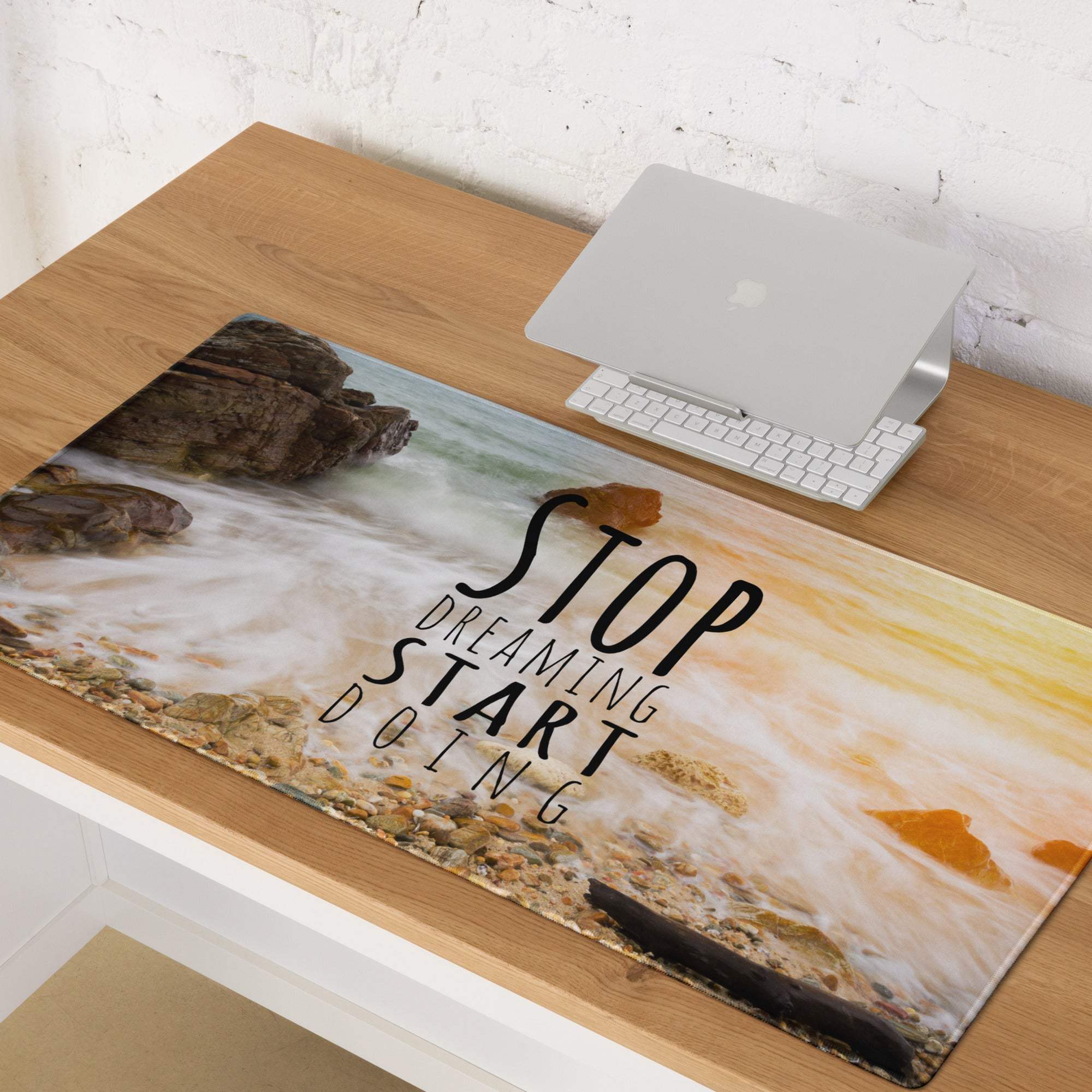 A rectangular glossy mouse pad with a sunset orange and ocean blue coastal scene and motivational text for office use