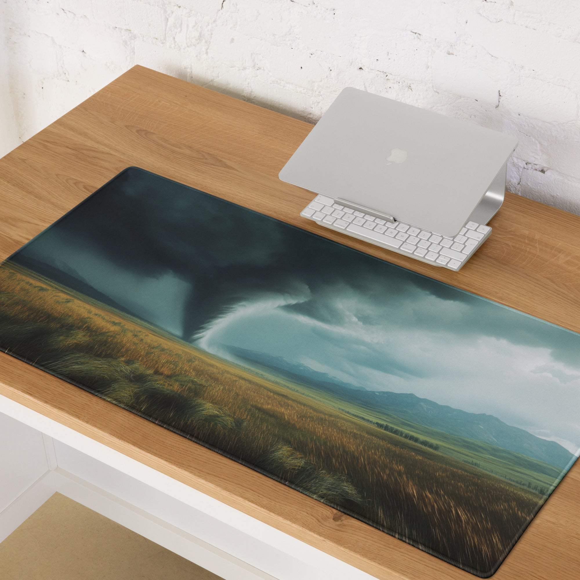 A dark teal and gold rectangular gaming desk mat featuring a printed tornado over a field for dramatic decor