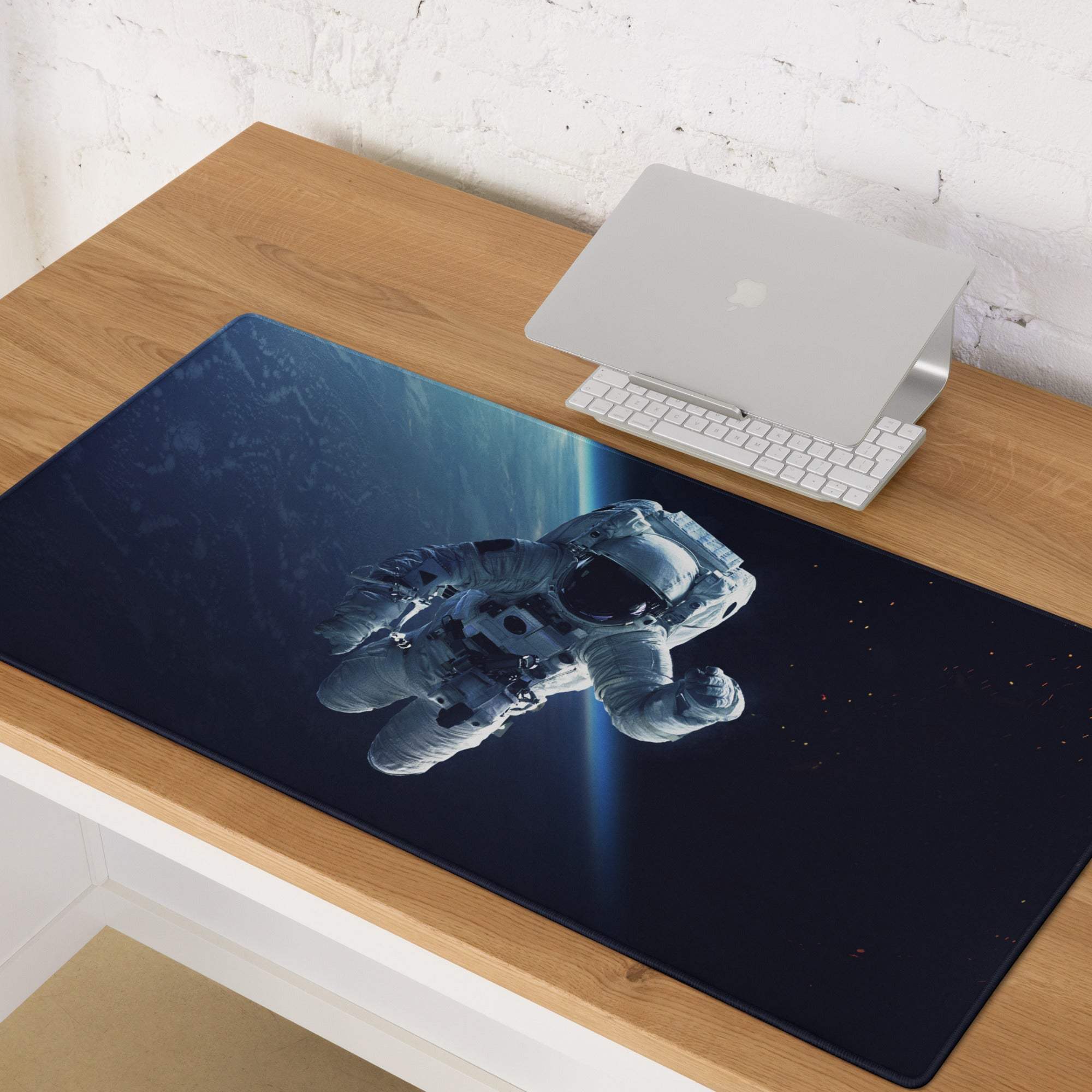 A sleek black gaming mousepad with a silver astronaut on a dark blue cosmic backdrop for space themed desks