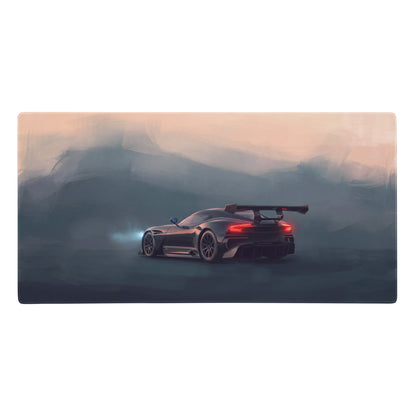 Aston Martin Vulcan inspired onyx track desk mat showing the rear of a black racing car with red taillights on misty mountains