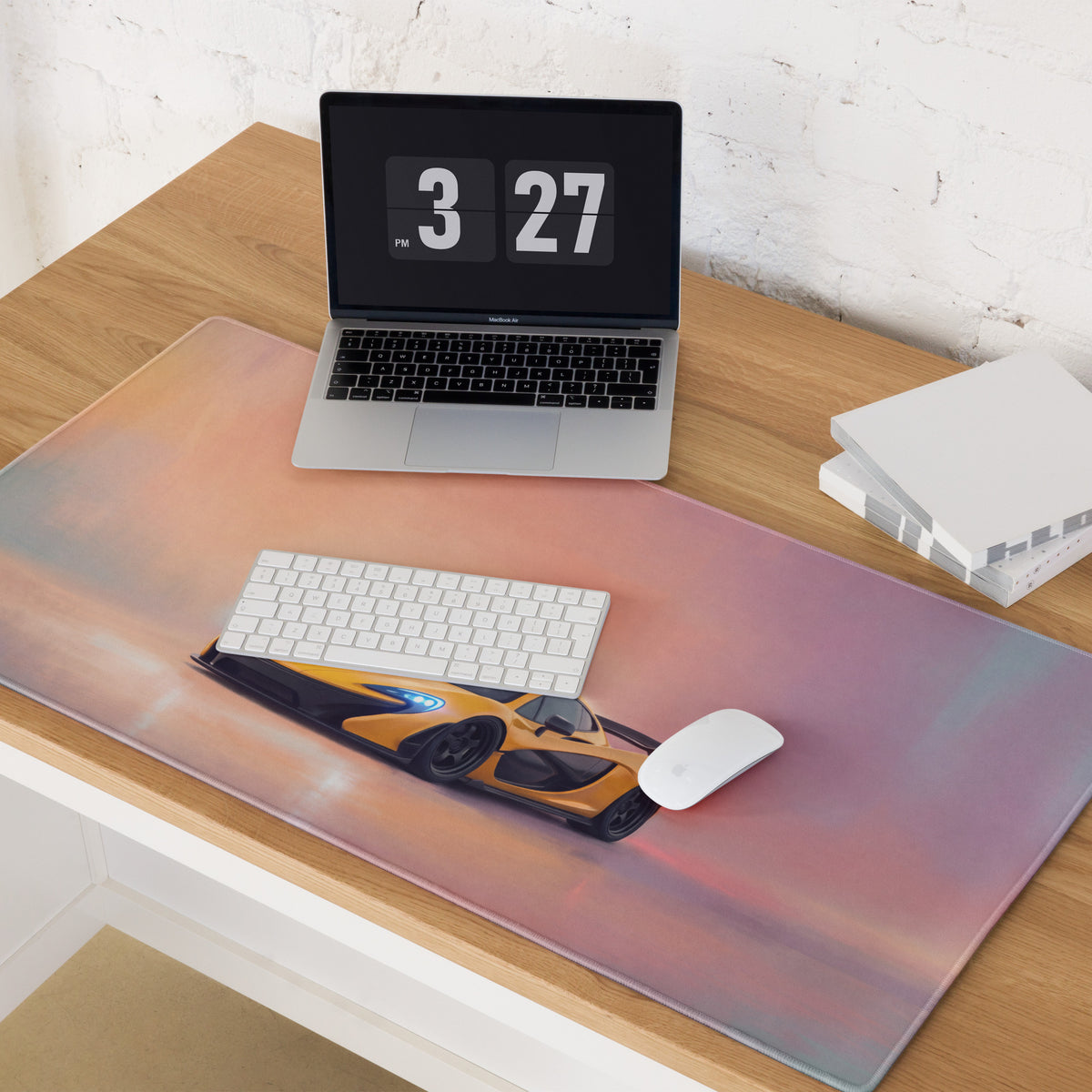 A sleek rectangular low-friction cloth desk mat featuring a vibrant orange mclaren p1 against a pink purple sky