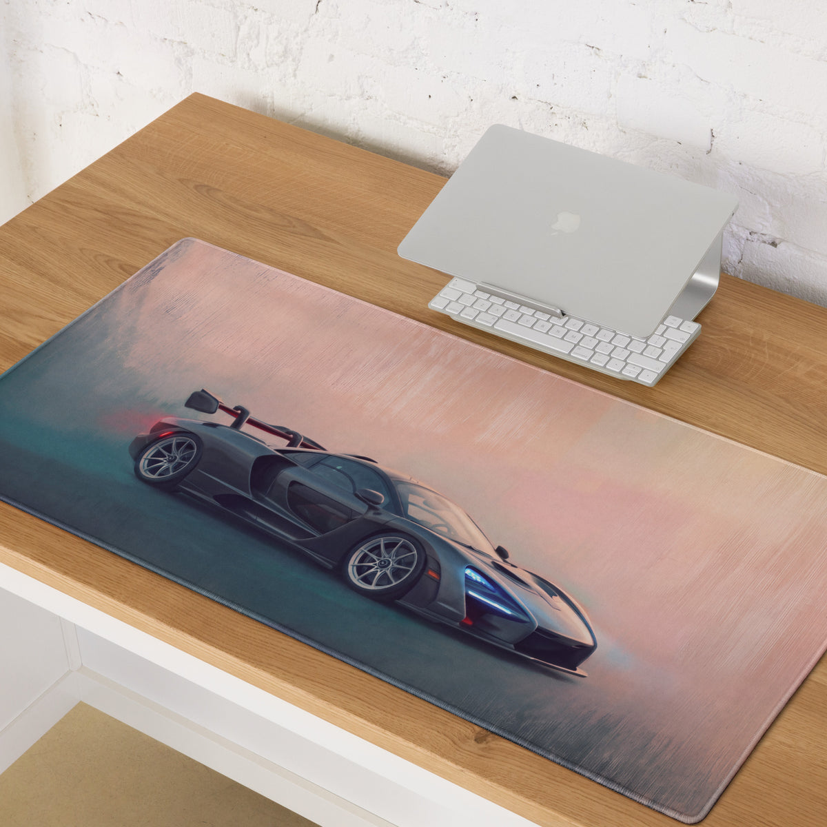 A sleek dark gray mclaren senna racing car graphic printed on a soft pink and teal gradient xl gaming mousepad