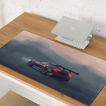 A sleek dark gray racing car with glowing red taillights on an aston martin vulcan inspired onyx track desk mat