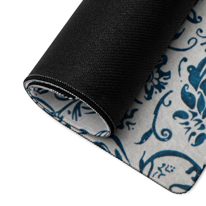 Rolled elegant blue damask rug back with black textured non-slip base on gray surface