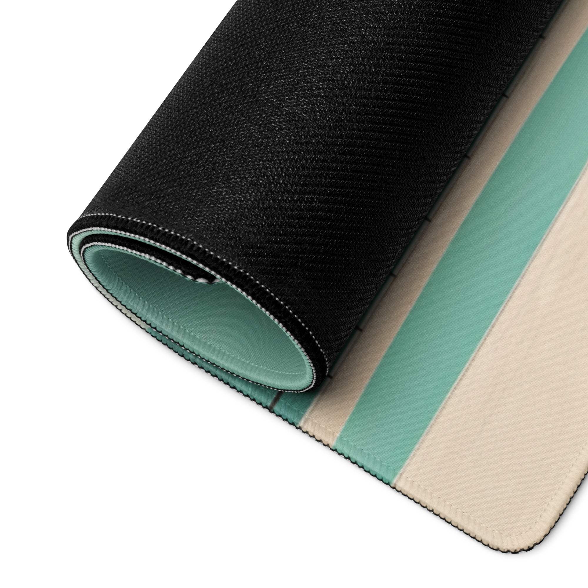 Black textured outer layer rolled to reveal teal cream interior of minimalist coastal gaming mouse pad