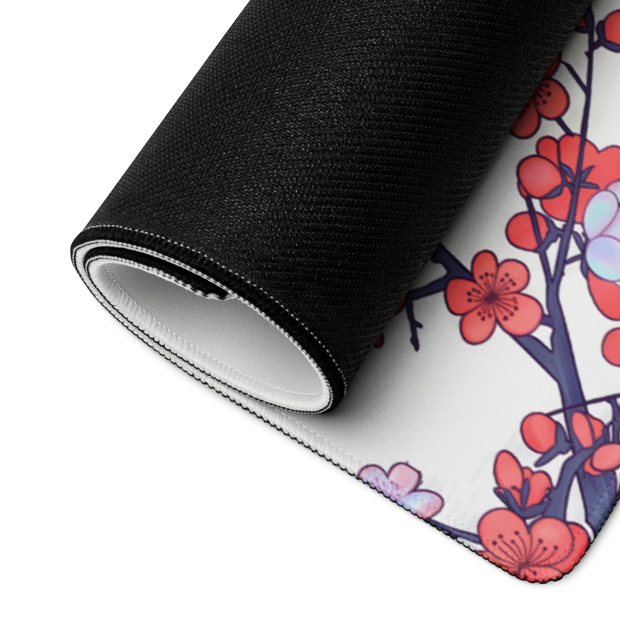 A rolled-up black and white gaming mousepad with vibrant pink cherry blossoms and dark blue branches for retro gaming desk use