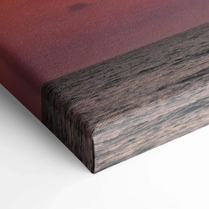Canvas wall art corner showing textured fabric with sunset gradient and dark wood grain print edges.