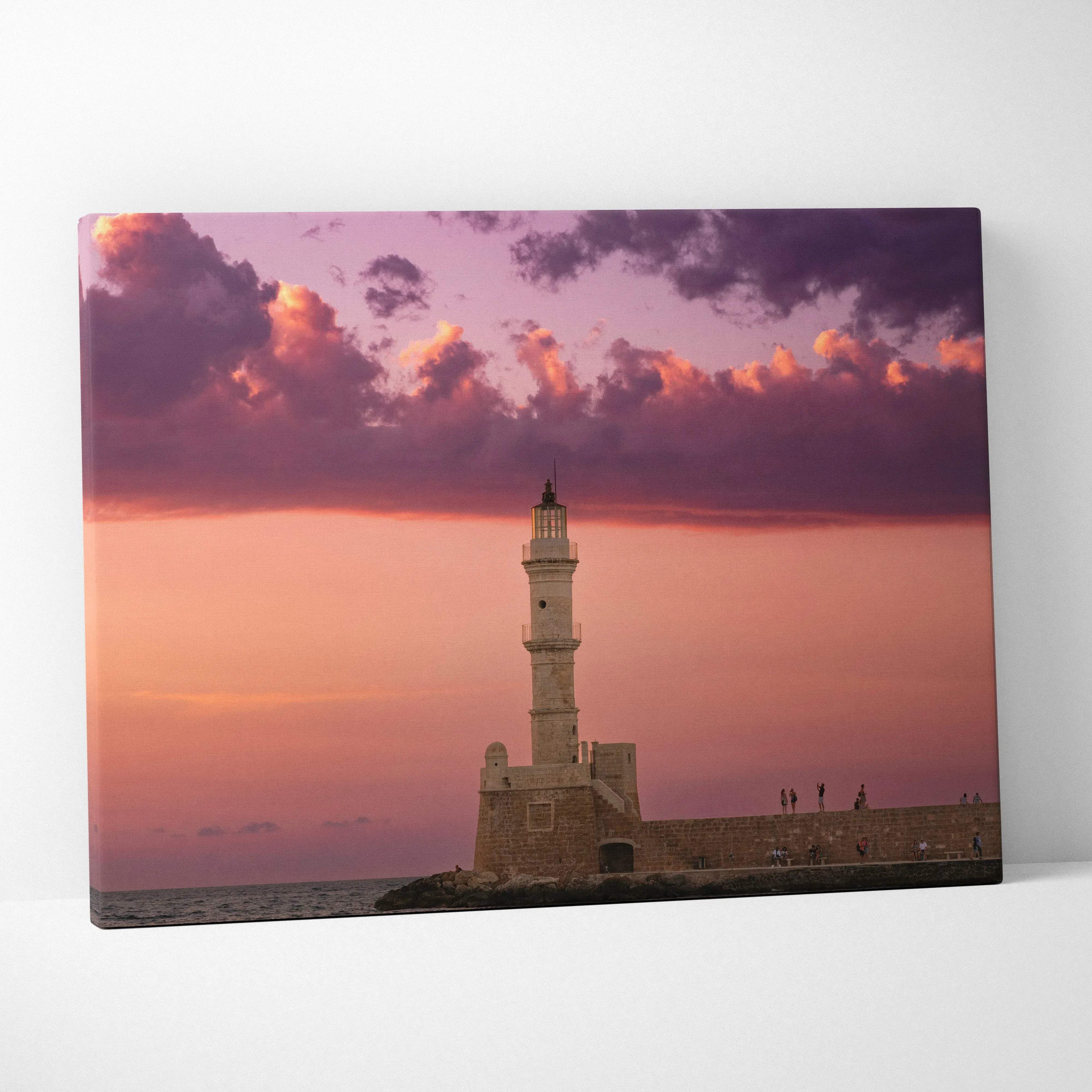 Rectangular canvas print of a historic stone lighthouse at sunset with warm pink and orange clouds in a romantic seascape