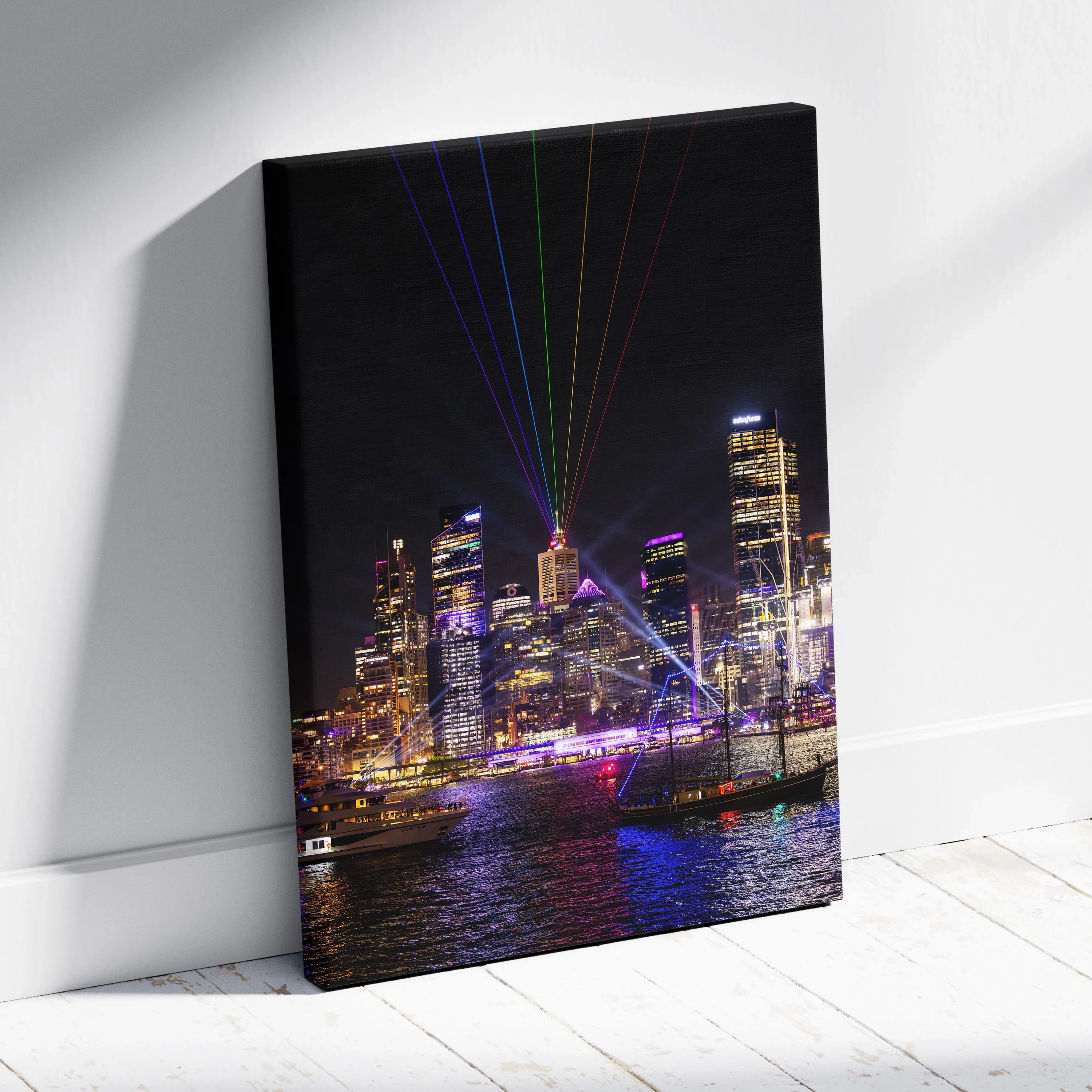 Vertical canvas wall art of a colorful urban skyline at night with laser lights above city buildings.